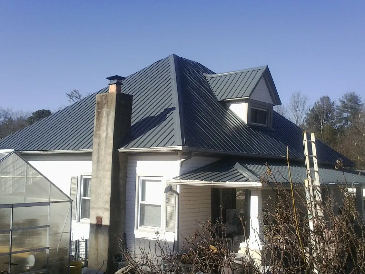Dark blue standing seam metal roof on a white farmhouse with dormer — Slate & Tile Roof Repair by Roofing Brothers in Apulia Station