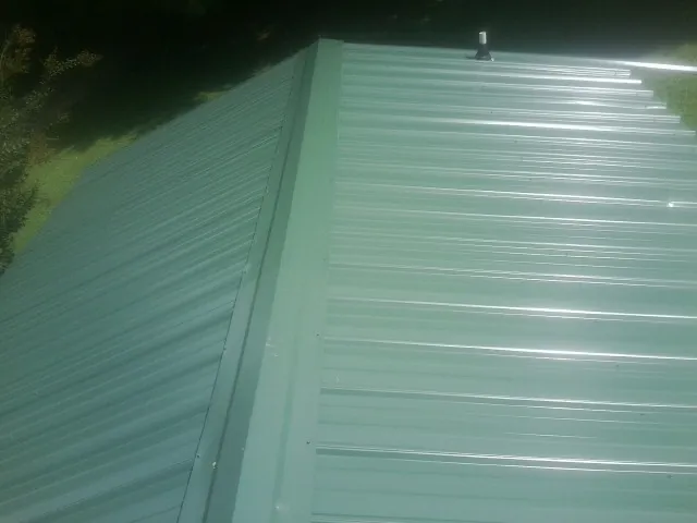 New green metal panels meeting at the ridge of a roof — Flat Roof Repair work by our crew in Apulia Station
