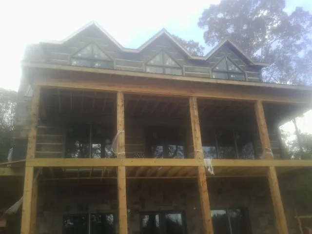 Dormers and porch framing on a large log home under construction — Roof Coating work by our crew in Apulia Station