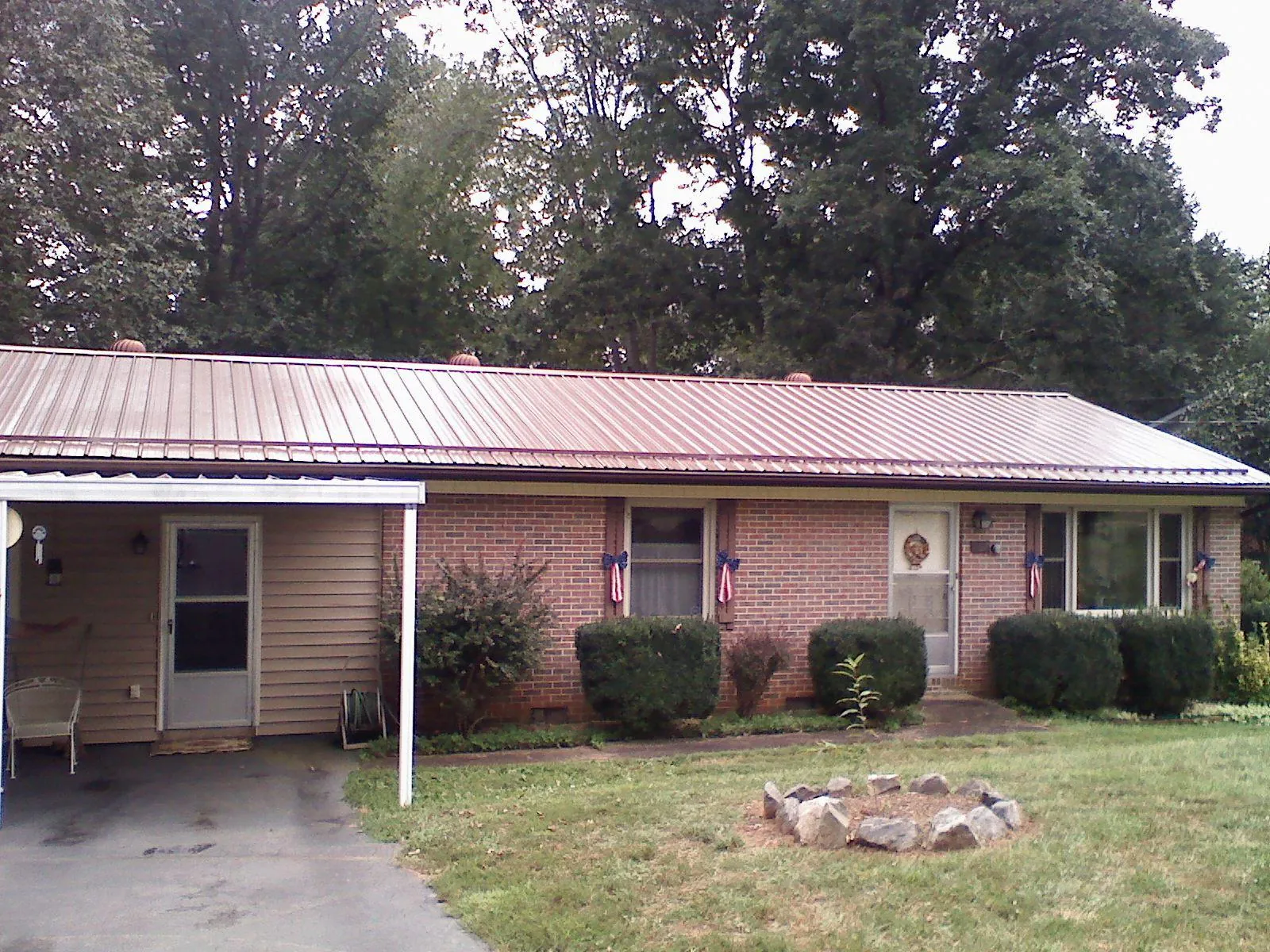 Bronze metal roof and carport on a brick ranch home — Roof Repair work by our crew in Apulia Station